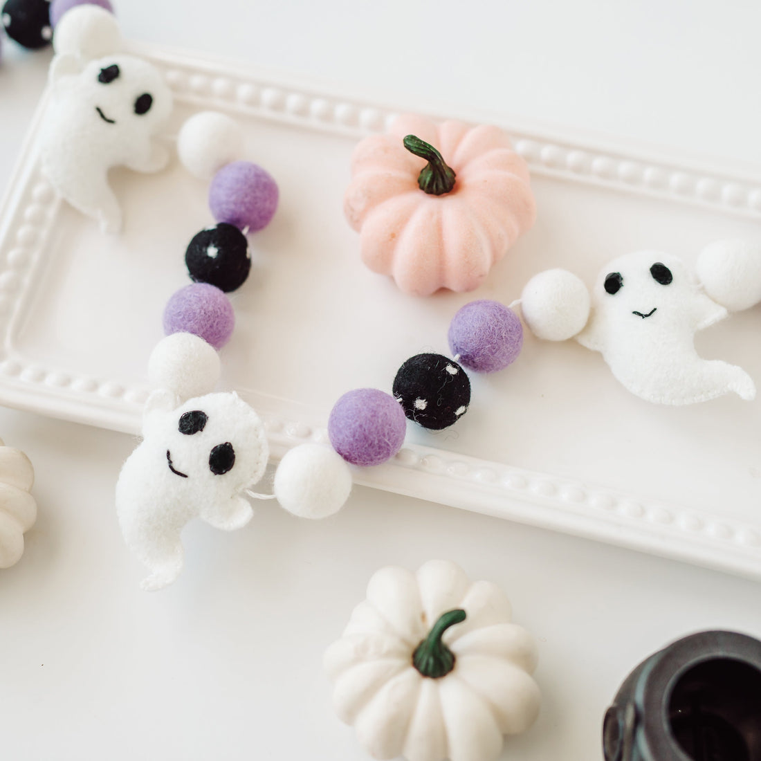 Decorative Halloween garland with ghost and pumpkin shapes on a white surface.